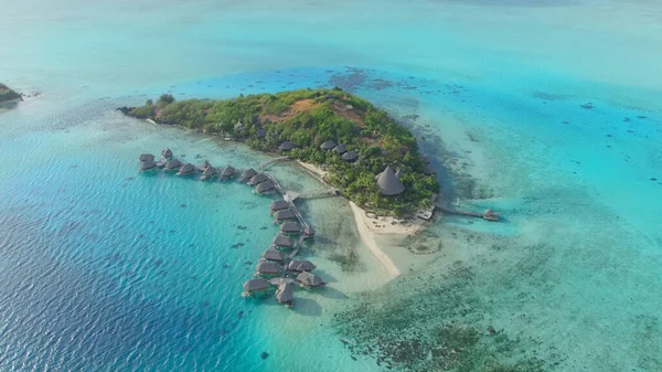 DRONE: volando in alto sopra fantastici bungalow sull'acqua su una piccola isola tropicale. — Foto Stock
