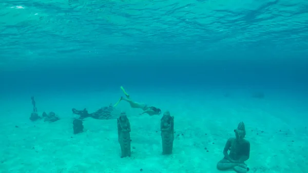 UNDERWATER: Curious female traveler diving around the ancient Buddha statues. — Foto Stock
