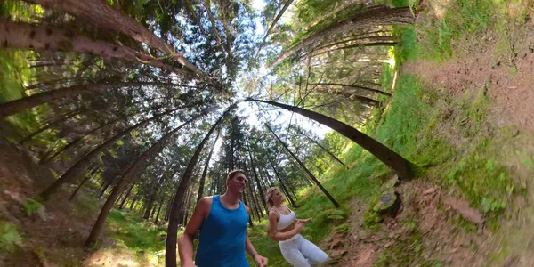 SELFIE, WIDE ANGLE: Glada joggingpar som springer genom den solbelysta skogen. — Stockfoto