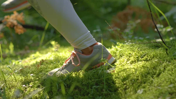 CLOSE UP, DOF: Fit woman jogging through the forest and along the mossy ground. — Foto de Stock