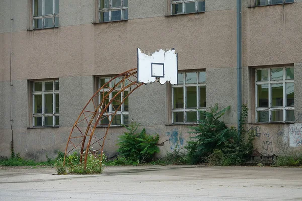 Stary kosz do koszykówki powoli rozpada się za starym opuszczonym apartamentowcem.. — Zdjęcie stockowe