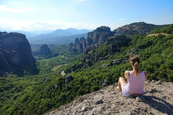 閉じる:崖の上に座って絵のような自然を観察する女性. — ストック写真