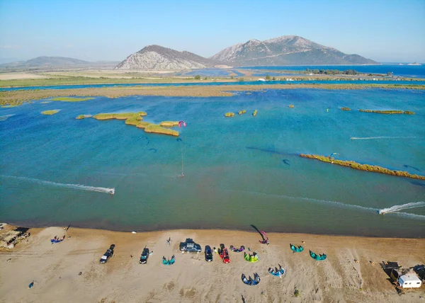 AERIAL: Turistas deportivos practican kitesurf alrededor de la bahía de viento en la costa griega . — Foto de Stock