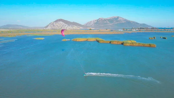 DRONE: Unrecognizable kitesurfer riding along the tranquil sea on a sunny day. — Foto de Stock