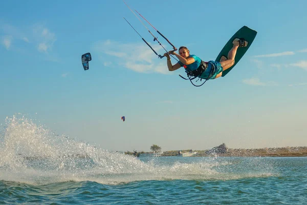 LOW ANGLE: Happy young woman jumps high in the air while kiteboarding in Greece. — Foto de Stock