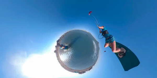 VR 360: Homem faz uma selfie como kiteboarder fêmea salta após ele em um dia ensolarado. — Fotografia de Stock