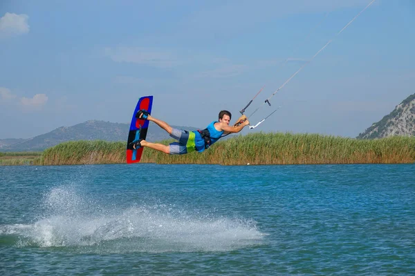 Extreme man on summer vacation having fun doing tricks while kiteboarding. — Foto de Stock