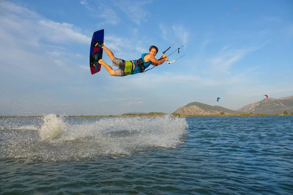 Cool kitesurfer catches a strong wind blowing along shore and jumps high in air. — Foto de Stock