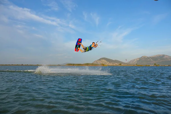 Breathtaking shot of athletic man jumping high in the air while kiteboarding. — Foto de Stock