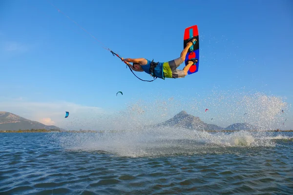 Young male tourist jumping and doing tricks while kitesurfing in sunny Greece. — Foto de Stock
