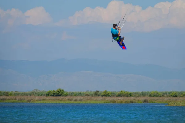 Unrecognizable man jumps in air as he kiteboards along the shoreline of Lefkas. — Foto de Stock
