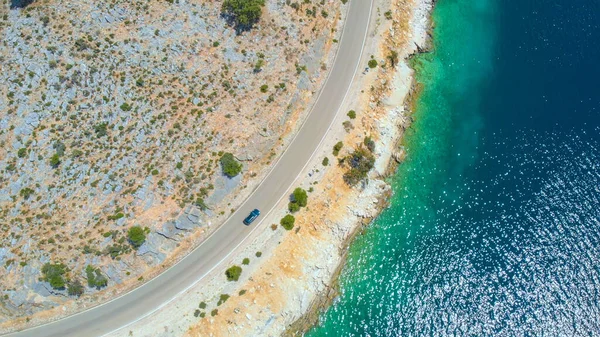 DRONE: Flying above tourist car driving along the beautiful glistening ocean. — Stock Photo, Image