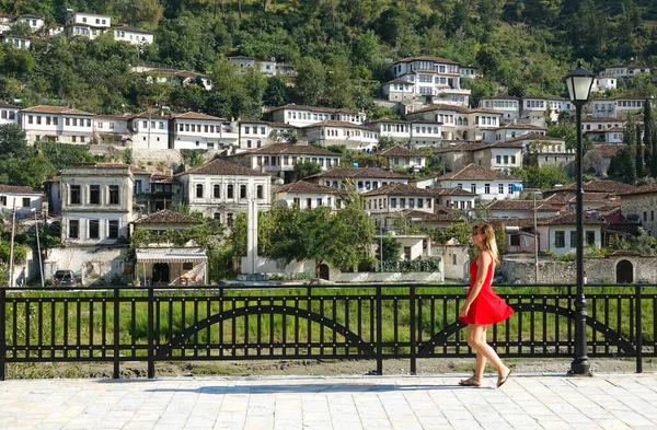 Young woman in red walks along the walkway under ancient Ottoman residences. — Stockfoto