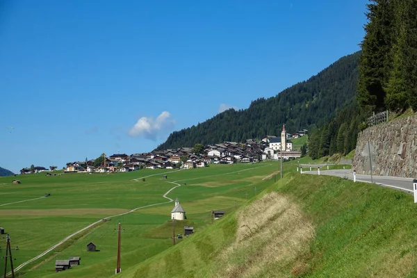 DRONE: Venkovská cesta vede kolem krásných zelených pastvin a k vesnici. — Stock fotografie