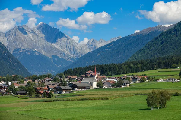AERIAL: Vliegen over de lege weiden en naar een idyllisch dorpje in Oostenrijk. — Stockfoto