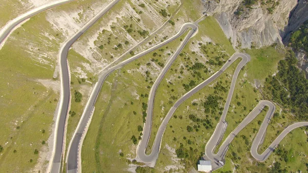 AERIAL: Tourist car driving up a winding asphalt road in the sunny Dolomites. — Foto de Stock