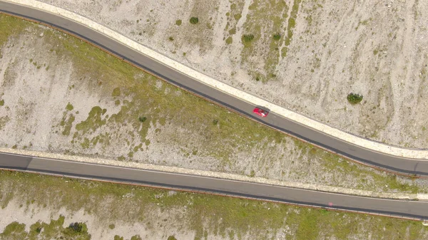 DRONE: Red sports car drives up a steep mountain road in the sunny Dolomites. —  Fotos de Stock