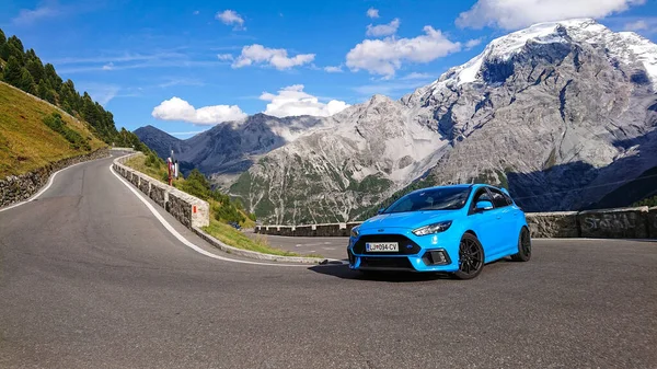 Cool baby blauw Ford Focus RS rijdt in een haarspeldbocht in de zonnige bergen. — Stockfoto