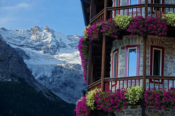 Beautiful shot of colorful flowers covering balcony of a hotel in the mountains — Stock Photo, Image