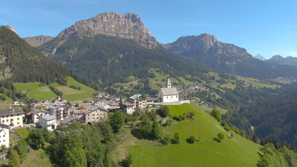 AERIAL: Katolický kostel s malým hřbitovem na vrcholu kopce v italských Alpách. — Stock fotografie