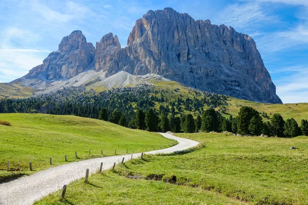 Empty gravel road leads towards the majestic rocky mountain in the Dolomites. — стоковое фото