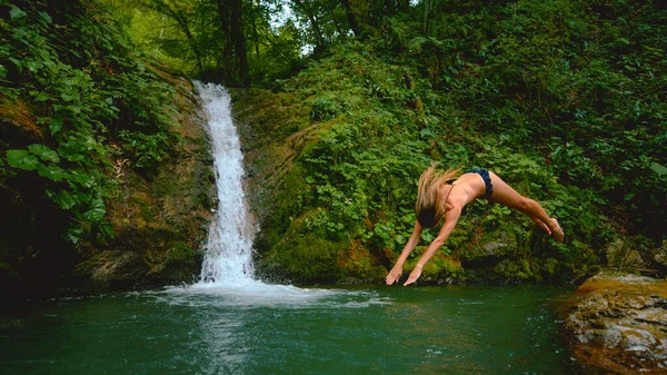 Oigenkännlig energisk kvinna dyker huvudet först i uppfriskande smaragdvatten. — Stockfoto