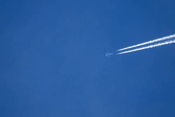 BOTTOM UP: Large commercial airplane leaves a white trail of exhaust fumes. — Foto Stock