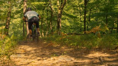 Tanınmayan bir adam dağ bisikletiyle toprak bir yolda hız yapıyor..