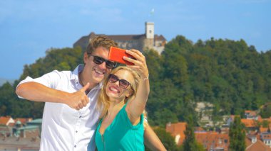 CLOSE UP: Joyful tourists pose while taking a selfie for their travel blog.