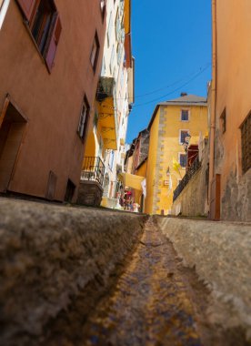 LOW ANGLE: Water flows down the drainage system in a colorful medieval town.