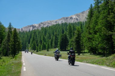Travelers on motorbikes enjoy a scenic road trip in the picturesque French Alps.