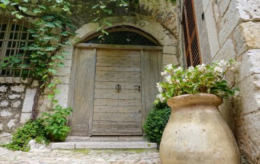 LOW ANGLE: White flowers grow in the clay pot in front of an old stone house.