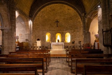 Bright yellow lights illuminate the inside of an old Catholic church in France.