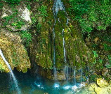 CLOSE UP: Breathtaking view of turquoise streams running down the mossy rocks.