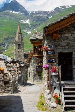 VERTICAL: Empty street leads past a cafe and towards a stone church in the Alps.