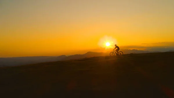 SILHOUETTE: L'uomo irriconoscibile accelera la discesa in mountain bike al tramonto . — Foto Stock