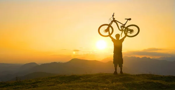 Neşeli adam, eğlenceli bir yolculuktan sonra dağ bisikletini başının üstünde tutuyor.. — Stok fotoğraf