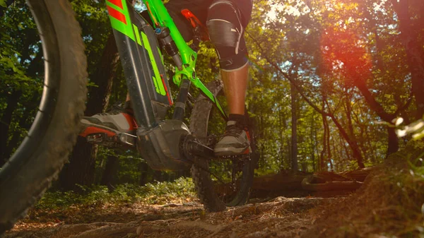 Genç erkek dağ bisikletçisi güneşli toprak bir yolda bisikletini sürüyor..