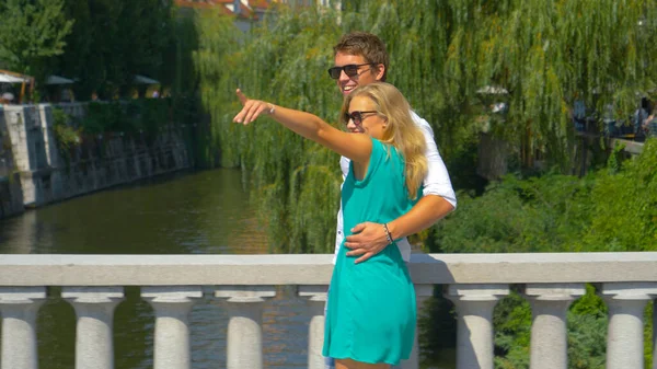 CLOSE UP: Young traveler couple in love walks across a bridge in Ljubljana. — Foto de Stock