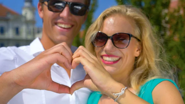 CLOSE UP: Young man and his girlfriend laugh and create a heart with their hands — Photo