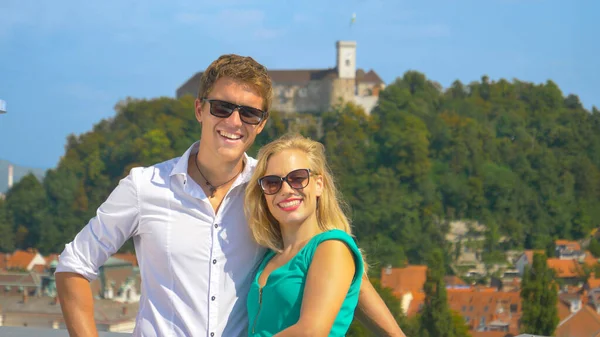 CLOSE UP: Joyful tourist couple poses on a rooftop in front of Ljubljana castle — Foto de Stock