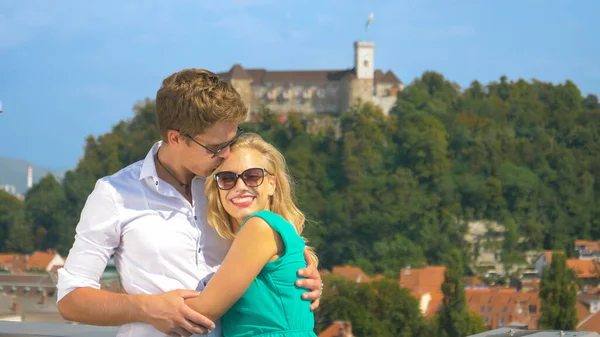 PORTRAIT: Happy man kisses his girlfriend on the forehead while observing city — Stock Photo, Image