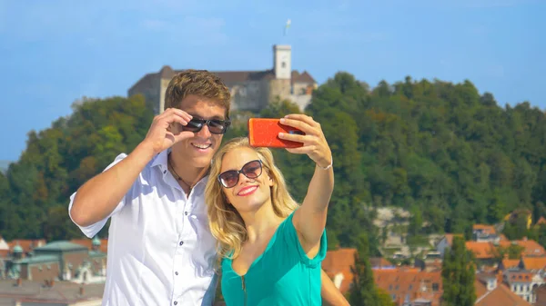 CLOSE UP: Happy girl holds up her smartphone to take a selfie with her boyfriend — Foto de Stock