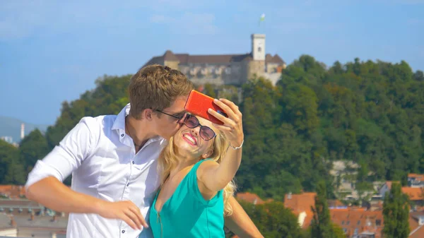 CERRAR: Hombre feliz besa a su novia en la mejilla mientras toma selfies . — Foto de Stock