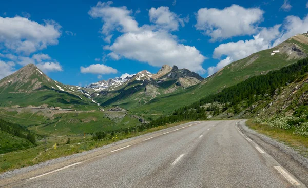 Empty asphalt road runs through the idyllic countryside in the French Alps.