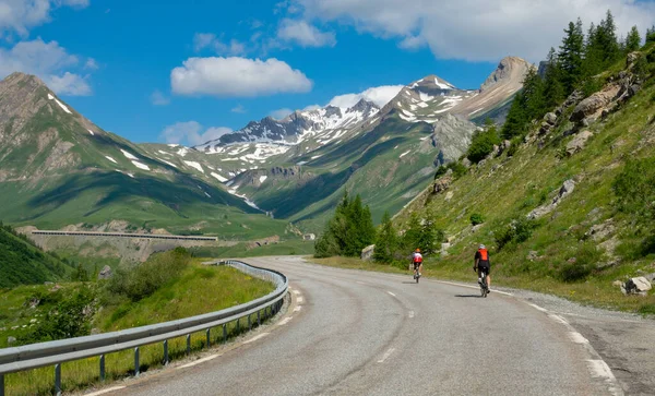 Two tourists riding bicycles along the scenic mountain road in rural France.