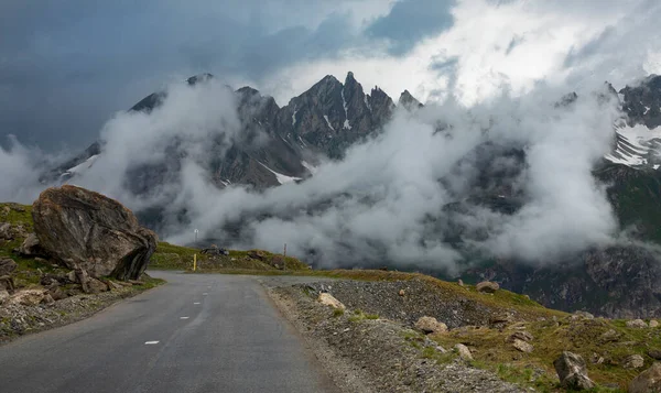 Empty asphalt road runs past the rocky mountains covered in the morning fog. — Φωτογραφία Αρχείου