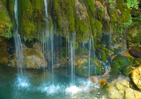 Kis patakok futnak le a zöld sziklákon keresztül a smaragd tóba.. — Stock Fotó