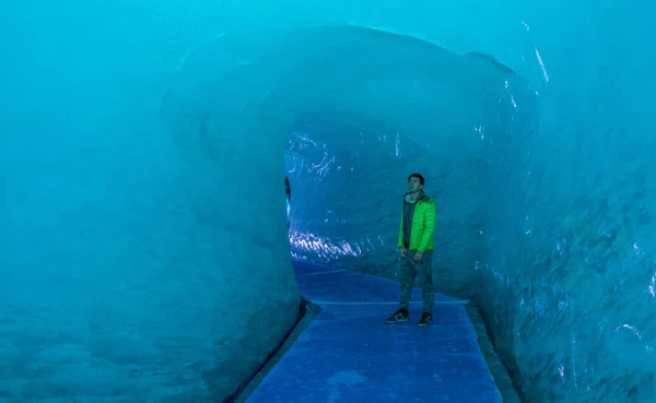 Manlig resenär observerar de isiga väggarna när han går genom en smältande glaciär. — Stockfoto