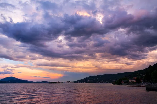 Clouds gather above lake Maggiore and coastal town on a sunny summer morning.